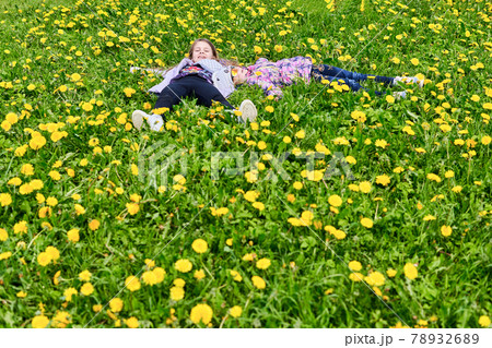 Two teenage girls lie in a field of yellow dandelions Two teenage girls lie in a field of yellow dandelions 78932689