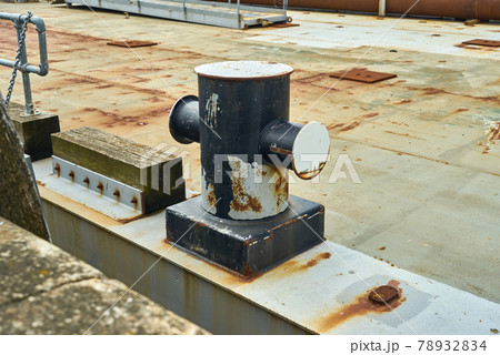 Side view of a cruciform mooring bollard showing signs of wear from ropes Side view of a cruciform mooring bollard showing signs of wear from ropes 78932834