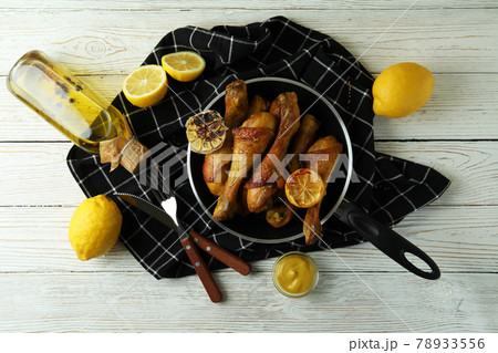 Concept of delicious eating with pan of roast chicken drumsticks on white wooden table Concept of delicious eating with pan of roast chicken drumsticks on white wooden table 78933556