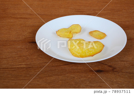 Dried and fried cassava slices place on white plate isolated on wood texture background. This is local Malaysian traditional junk food call Kerepek Ubi.  78937511