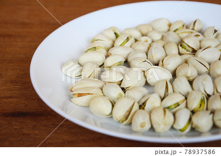 Plate of salted pistachio nuts on wood texture background. Plate of salted pistachio nuts on wood texture background. 78937586