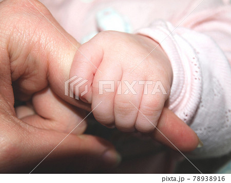 A baby with a small hand holds mom's finger 78938916