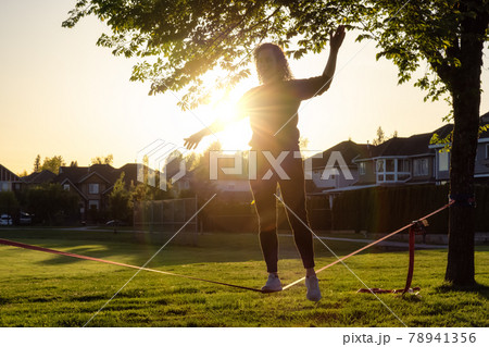 Adventurous White Caucasian Adult Woman walking on a Slackline Adventurous White Caucasian Adult Woman walking on a Slackline 78941356