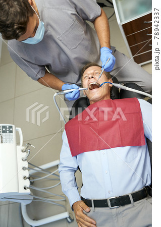 Qualified dentist monitoring teeth of his male patient Qualified dentist monitoring teeth of his male patient 78942337