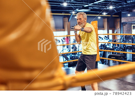 Best cardio. Athletic mature man in sportswear boxing while standing on the ring at gym 78942423