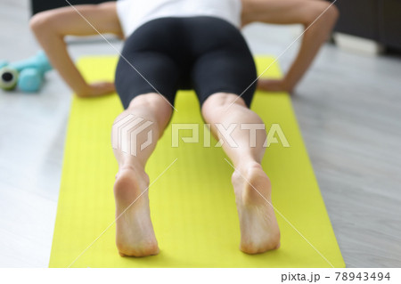 Young sportive woman doing push-ups on mat at home Young sportive woman doing push-ups on mat at home 78943494