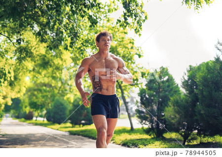 A strong attractive man running shirtless outside in the park A strong attractive man running shirtless outside in the park 78944505
