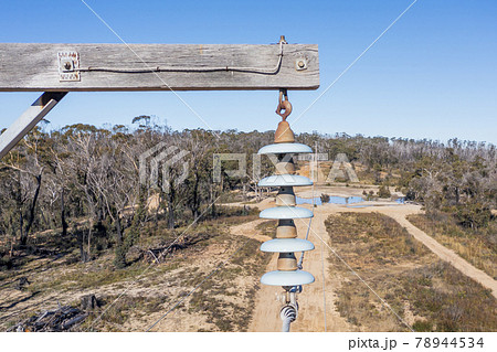 Drone aerial photograph of a wooden telephone pole and wires in a forest 78944534
