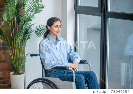 Young dark-haired handicapped woman looking thoughtful Young dark-haired handicapped woman looking thoughtful 78944594