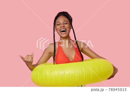 Smiling african american woman holding a yellow tube and having fun Smiling african american woman holding a yellow tube and having fun 78945015