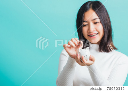 woman holding piggy bank on hands and putting coin 78950312