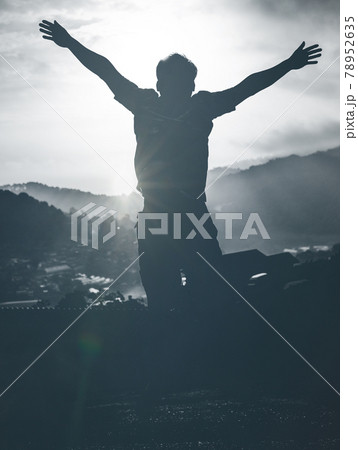 Hikers in silhouette stands on the rock in the beautiful mountains with rising hands at sunrise sky background Hikers in silhouette stands on the rock in the beautiful mountains with rising hands at sunrise sky background 78952635