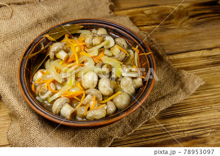 Delicious marinated mushrooms with carrot, onion and spices in ceramic bowl on wooden table 78953097