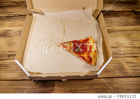 Last slice of pizza in cardboard box on a wooden table. Concept for home delivery of food, fast food, delivery of pizza Last slice of pizza in cardboard box on a wooden table. Concept for home delivery of food, fast food, delivery of pizza 78953115