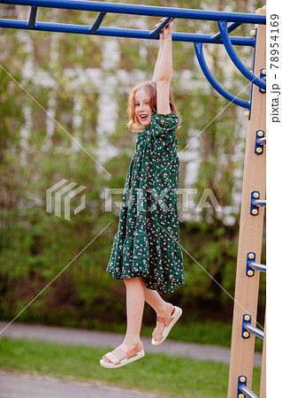Smiling child hanging on monkey bars outdoors 78954169