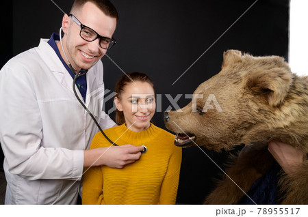 smiling young man doctor with stethoscope and patient examining bear, studio smiling young man doctor with stethoscope and patient examining bear, studio 78955517