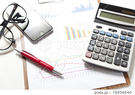 Financial accounting stock market graphs and charts analysis with pen and calculator on table. 78956640