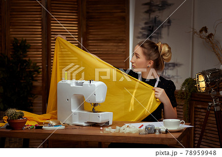 Beautiful young seamstress working on sewing machine 78959948