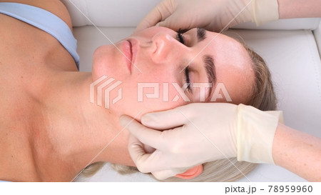 Facial massage beauty treatment. Close up of a young womans face lying on back, getting face lifting 78959960