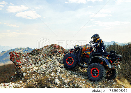 Man in helmet sitting on ATV quad bike in mountains Man in helmet sitting on ATV quad bike in mountains 78960345