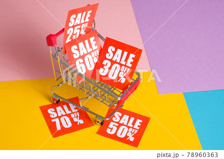 Online shopping discount concept. Red labels with percents in trolley on a multicolored background. 78960363