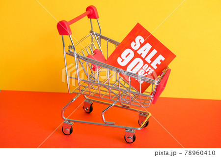Trolley on a red-yellow background with the announcement of a 90% discount. The concept of sales. 78960410