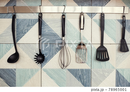 Kitchen spatulas handing on railing on a tiled wall with blue geometric pattern Kitchen spatulas handing on railing on a tiled wall with blue geometric pattern 78965001