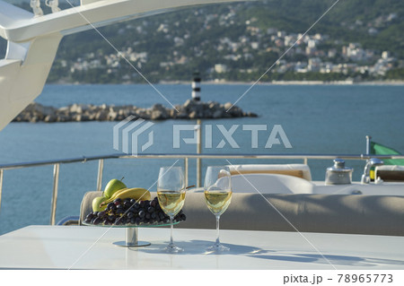 Wine and fruit on a table on the deck of a cruise yacht Wine and fruit on a table on the deck of a cruise yacht 78965773