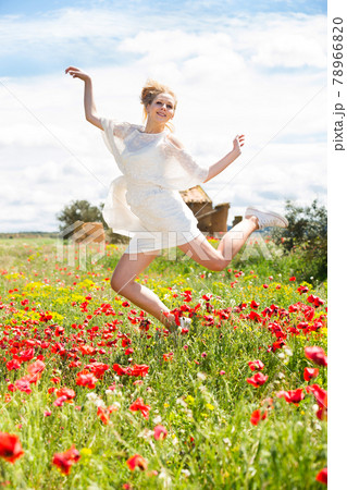 Happy young female jumping in poppy field 78966820