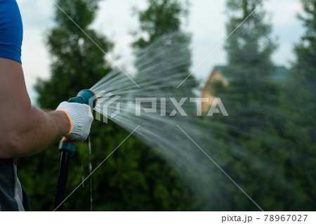 Gardening and maintainance- close up of man hands with hose watering the lawn 78967027