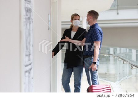 Man and woman wearing protective medical masks opening door to hotel room Man and woman wearing protective medical masks opening door to hotel room 78967854