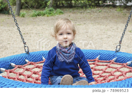 Cute little child having fun on a colorful swing outdoor in the park. Beautiful spring day in children playground Cute little child having fun on a colorful swing outdoor in the park. Beautiful spring day in children playground 78969523