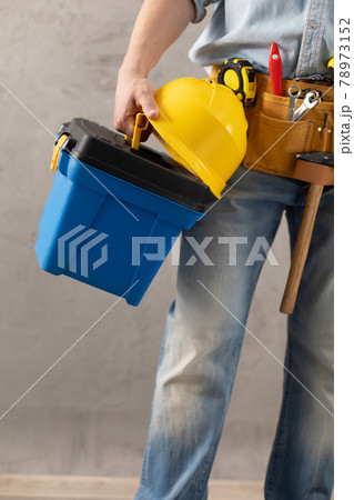 Man worker holding construction helmet and toolbox near wall. Male hand and construction tools 78973152