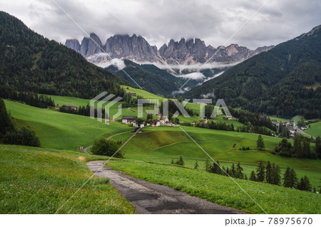 Hiking trail to St Magdalena church in Val di Funes valley, Dolomites, Italy. Furchetta and Sass Rigais mountain peaks in background Hiking trail to St Magdalena church in Val di Funes valley, Dolomites, Italy. Furchetta and Sass Rigais mountain peaks in background 78975670