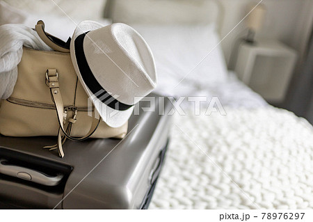 Gray suitcase with handbag and summer hat packing ready to travel vacation on bed at home or hotel Gray suitcase with handbag and summer hat packing ready to travel vacation on bed at home or hotel 78976297