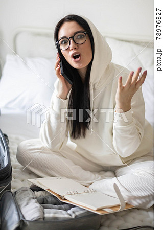 Smiling woman talking mobile phone making list notes of things ready to summer travel vacation Smiling woman talking mobile phone making list notes of things ready to summer travel vacation 78976327