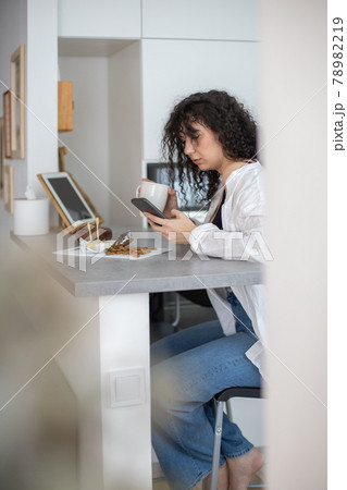 Young domestic feminine typing message texting communicate social networks at white nordic kitchen Young domestic feminine typing message texting communicate social networks at white nordic kitchen 78982219