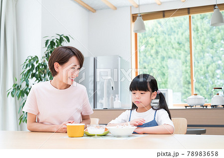 キッチンテーブルで母親の隣で食事する女の子 78983658