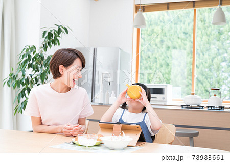 キッチンテーブルで母親の隣で食事する女の子 キッチンテーブルで母親の隣で食事する女の子 78983661