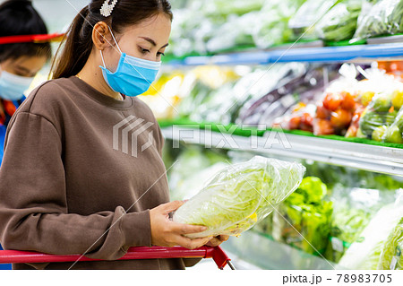 Young asian woman with protective mask pushing shopping cart for buying fresh vegetables in supermarket during virus COVID-19 outbreak. Concept for prevention COVID-19 Virus. 78983705