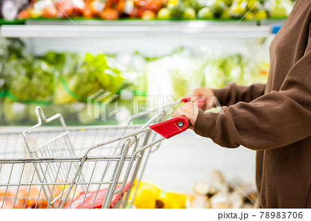 Young woman pushing shopping cart for buying fresh vegetables in supermarket. Young woman pushing shopping cart for buying fresh vegetables in supermarket. 78983706