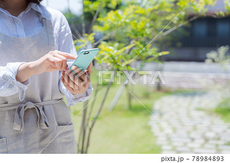 庭先でスマホを持つ女性の手元 78984893