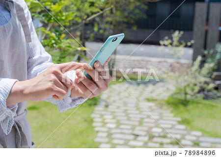 庭でスマホを操作をする手元 78984896