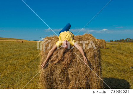a girl is sunbathing in the hay. village life: harvesting hay for the winter. animal feed. a girl is sunbathing in the hay. village life: harvesting hay for the winter. animal feed. 78986022