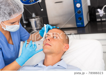 Man receiving cosmetic facial injection in clinic Man receiving cosmetic facial injection in clinic 78986023