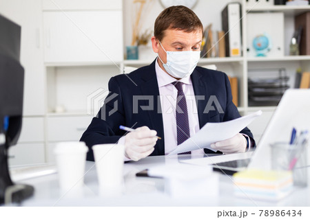 Businessman in face mask and gloves working in office 78986434