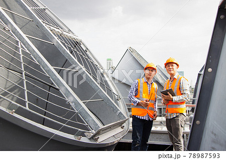 Asian male engineer inspecting pipe fittings and chillers, refrigeration plant refrigeration plant in  factory. male mechanic wearing helmet and Reflective Safety Vest uses laptop, tablet, equipment 78987593