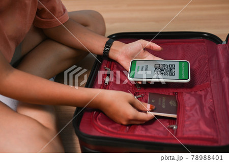 Woman traveler holding mobile phone with health passport and getting ready for departure. 78988401