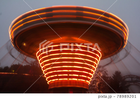 A blurry chain carousel in motion at the amusement park, evening illumination. The effect of bokeh and long exposure. 78989201