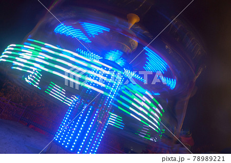 A blurry colorful carousel in motion at the amusement park, night illumination. The effect of bokeh and long exposure. 78989221